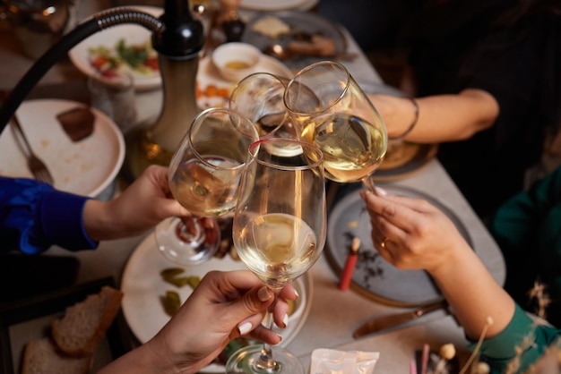 Girlfriends drinking wine and cheering while sitting in the bar Selective focus on glasses