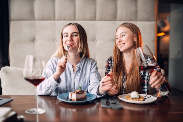 ガールフレンドは飲み物を飲み、カフェで甘いデザートを食べます。チョコレートケーキとテーブルの上のアルコール