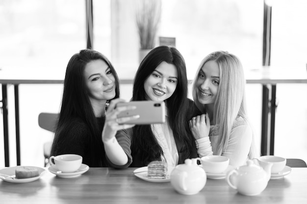 Girlfriends making selfie in cafe