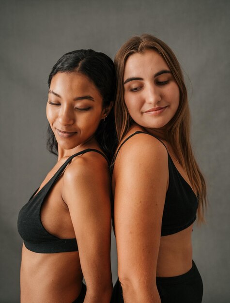 Girlfriends standing back to back posing in the studio