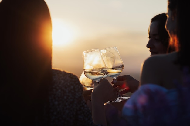 Photo girlfriends toasting glasses with wine at sunset