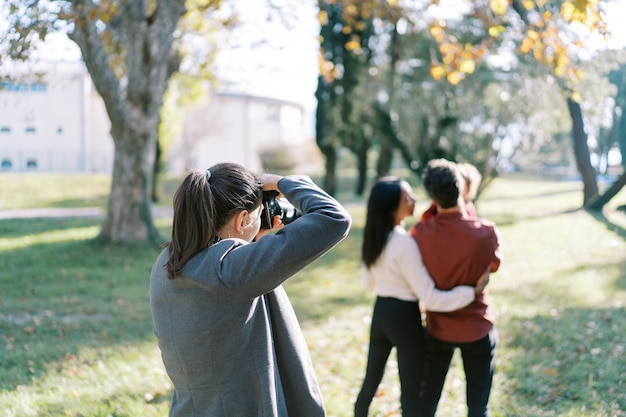 Girlphotographer takes pictures of parents with a little girl in their arms back view