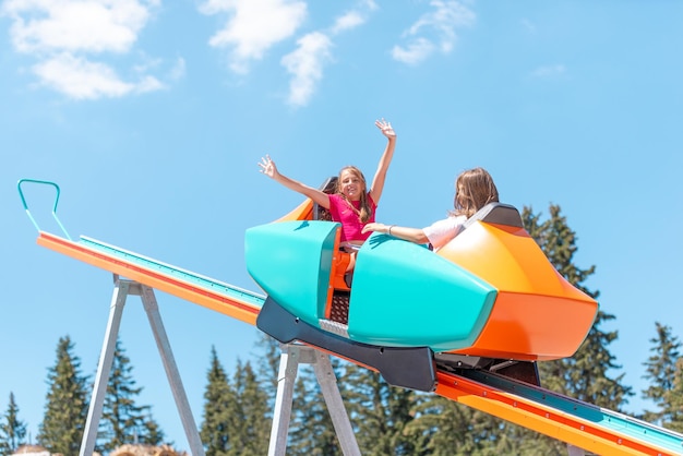 Girls are riding a mountain coaster with outstretched arms