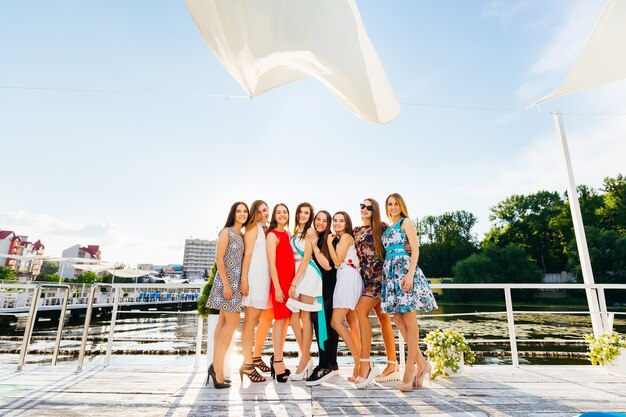 Girls in the beautiful dresses hug on the pier