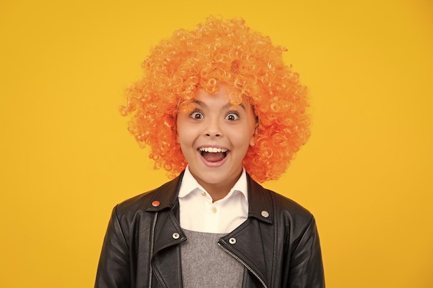 Photo girls birthday party funny kid in curly redhead wig time to have fun teen girl with orange hair being a clown excited face cheerful emotions of teenager girl