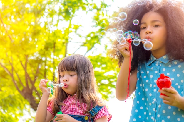 Girls blowing bubbles against trees