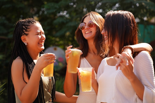 Le ragazze chiacchierano e bevono cocktail sulla terrazza estiva, foto lifestyle