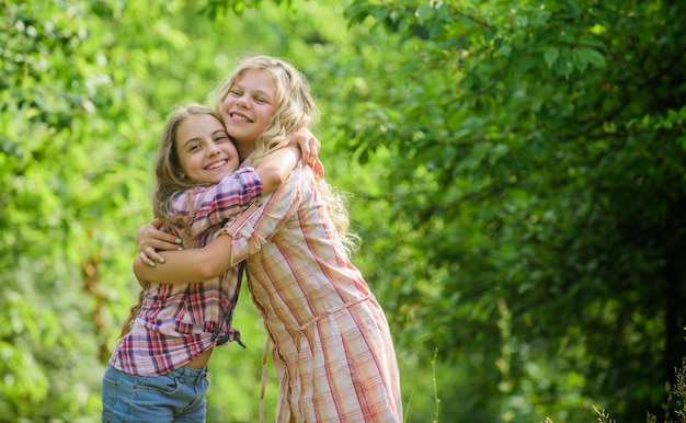 女の子の子供たちの親友は姉妹の愛とサポートを抱きしめます幸せな子供時代の抱擁と愛の概念子供たちは一緒に幸せ自然の背景真の友情幸せな顔をしている女の子はお互いを抱きしめます