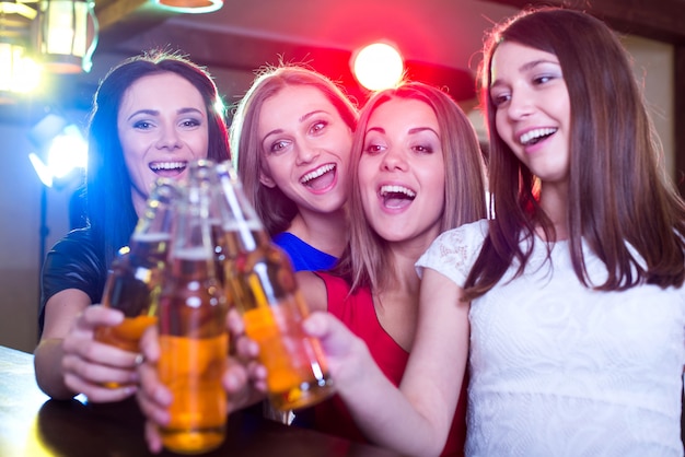 Girls clink glasses of beer in the club.