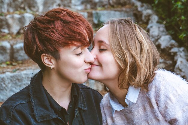 Photo girls couple in love kissing on the stone stairs in a park