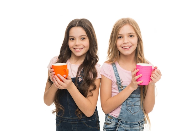 Girls cute children long hair drink cocoa or tea. Schoolgirls with mugs having tea break. Relax and recharge. Water balance concept. Enjoying tea together. Sisters or friends drink water. More energy.