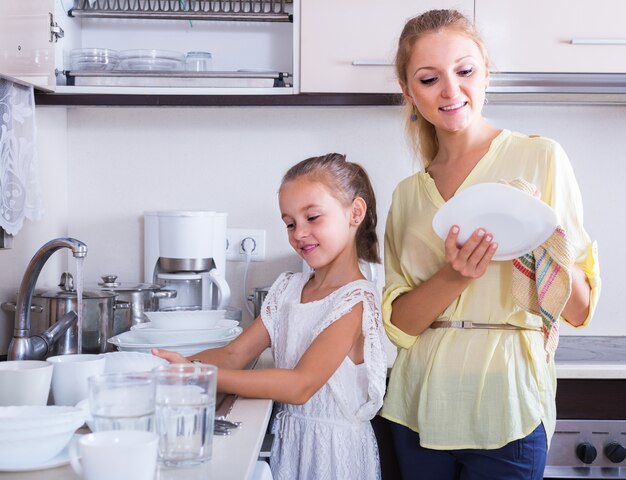 Photo girls doing and wiping dishes in kitchen