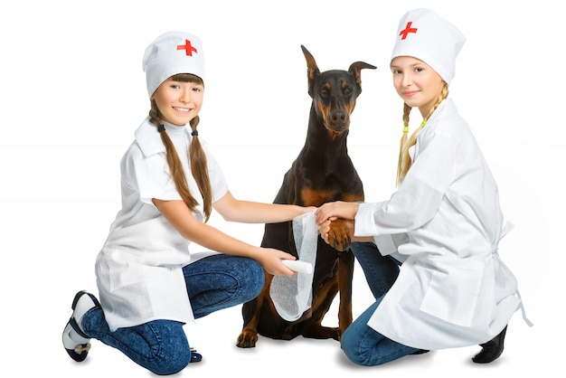 Girls dressed as doctor treating dog