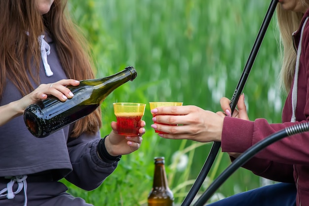 女の子は川のほとりで自然の中でワインを飲みます。自然。セレクティブフォーカス