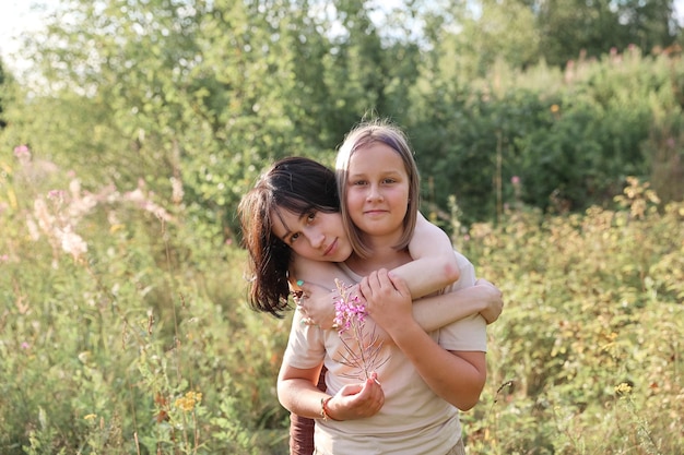 Girls in gathering wildflowers in sunset light, walking in summer meadow. Atmospheric authentic moment. Hand picking up flowers in countryside. Rural slow life