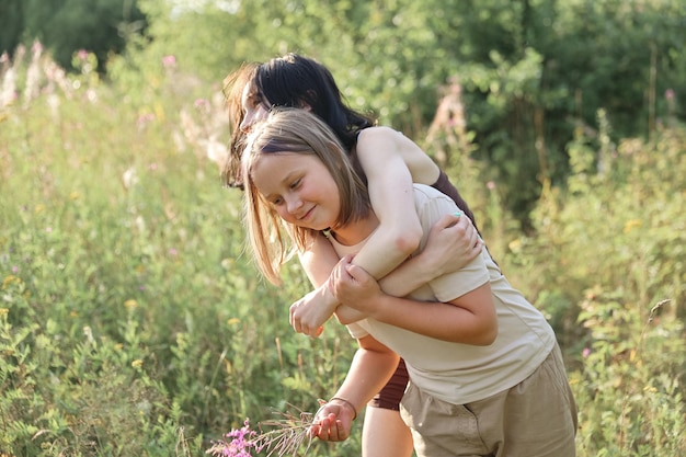 Girls in gathering wildflowers in sunset light, walking in summer meadow. Atmospheric authentic moment. Hand picking up flowers in countryside. Rural slow life