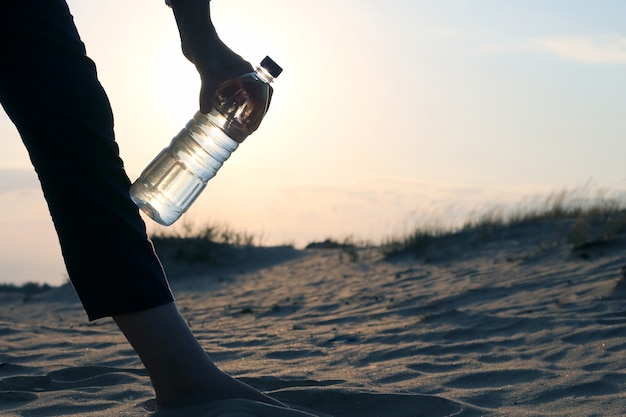 Девушки рука бутылку воды в пустыне