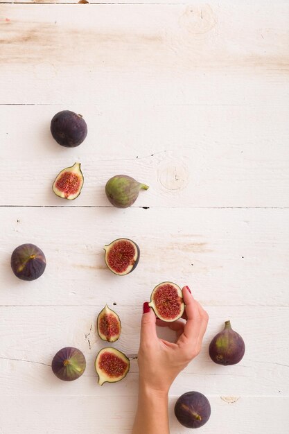 Girls hand taking sliced figs from white wooden table or background Healthy snack and food