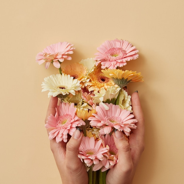 The girls hands hold a beautiful bouquet of gerberas on a yellow paper background