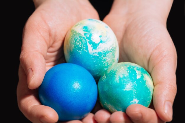 Girls hands hold three chicken Easter multicolored eggs of blue colors