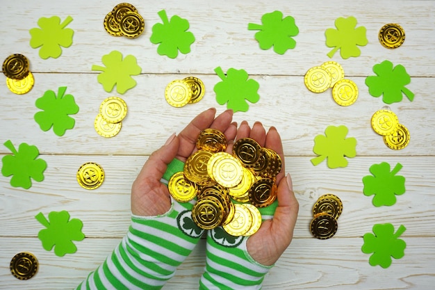 The girls hands in striped gloves hold coins with a fourleaf clover