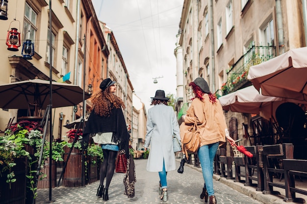 Le ragazze si divertono. colpo all'aperto di tre giovani donne che camminano sulla strada della città. vista posteriore