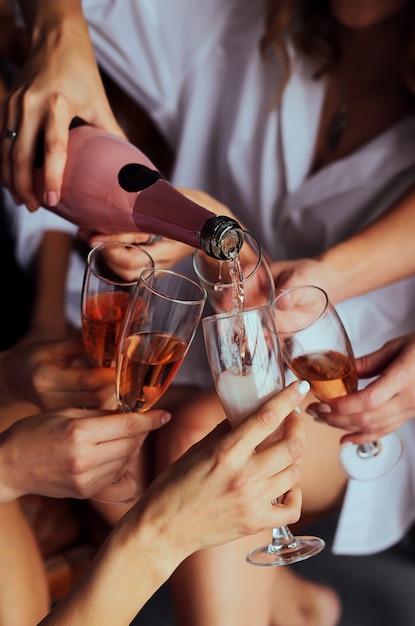 Girls hold in hands glasses with champagne, friends celebrating\
and toasting. beautiful female hands.