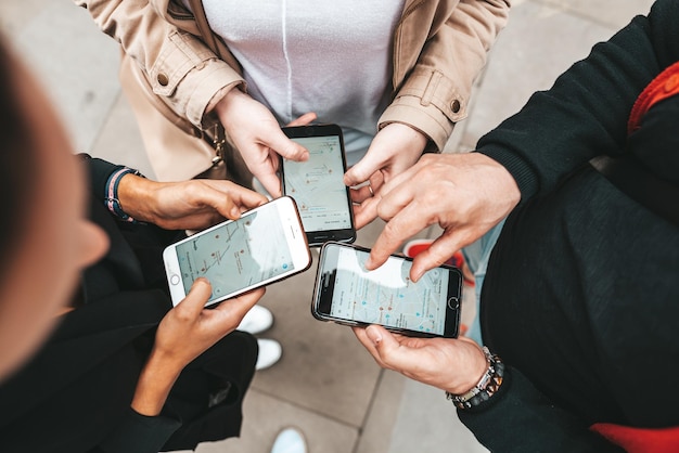 Girls look at a map on their phones and plots a route for a trip for a gps navigator