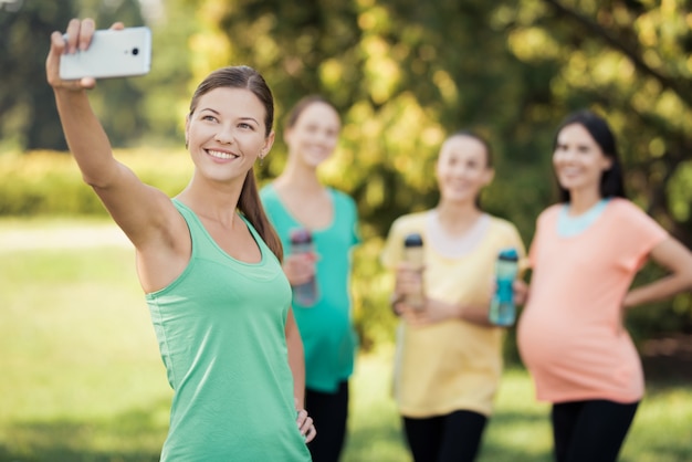 女の子は、スマートフォンで妊娠中の笑顔でSelfieを作ります。