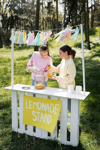 Girls making lemonade together full shot