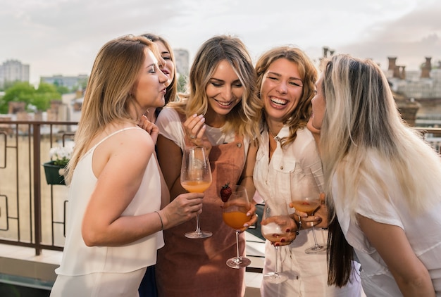 Girls Party. Beautiful Women Friends on the balcony Having Fun At Bachelorette Party. They are Celebrating And Drinking Champagne At Hen Party. Cheers