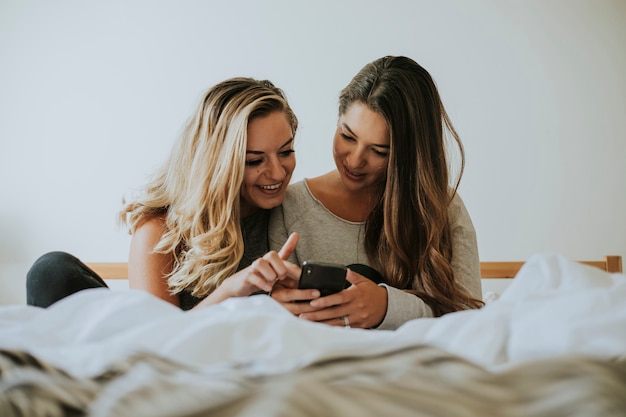 Ragazze che giocano con un telefono a letto