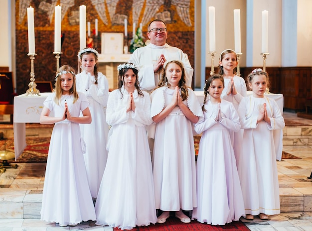 Ragazze e sacerdote durante la prima comunione