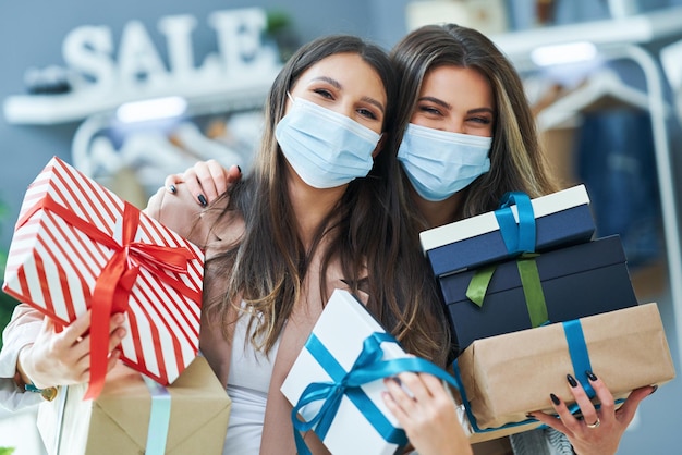 Girls on shopping in store with clothes wearing masks. High quality photo