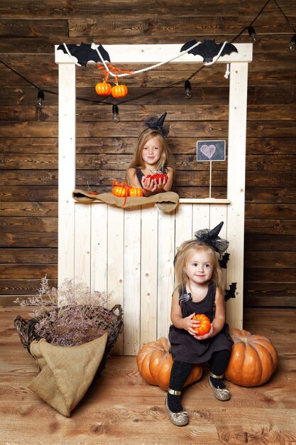 Girls sisters in witch costumes with Halloween decorations