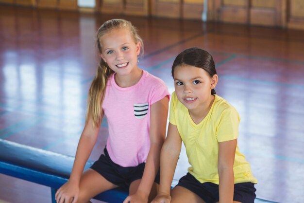 Girls sitting on bench in basketball court