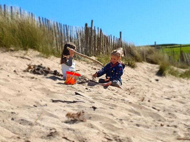 Foto ragazze sedute sulla sabbia sulla spiaggia