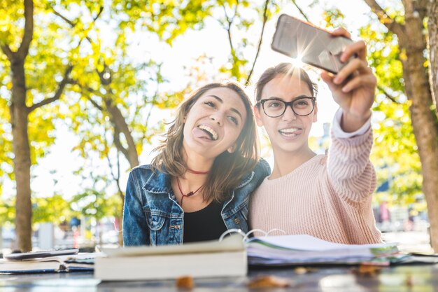 Ragazze che studiano e prendono un selfie divertente al parco