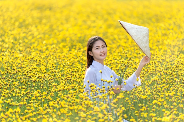 黄色の花畑で遊ぶベトナムの伝統的な民族衣装の女の子