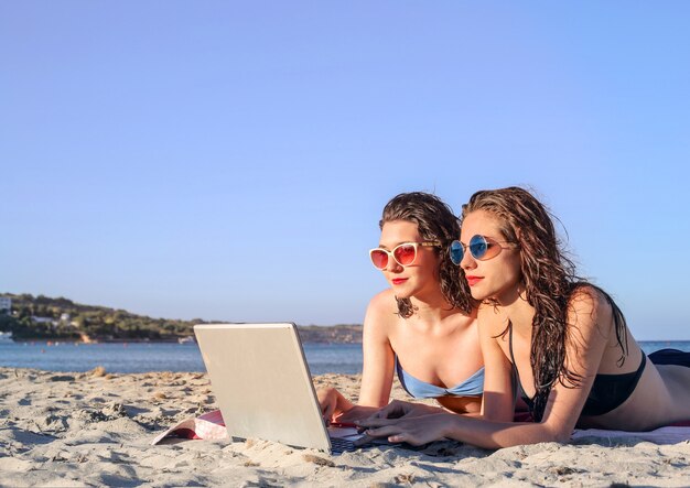 Девушки с ноутбуком на пляже
