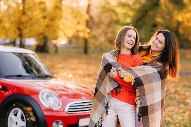 Girls walking in autumn park in red car autumn mood concept