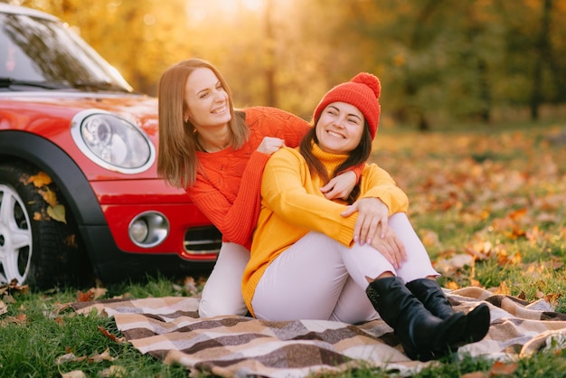 Girls walking in autumn park in red car autumn mood\
concept