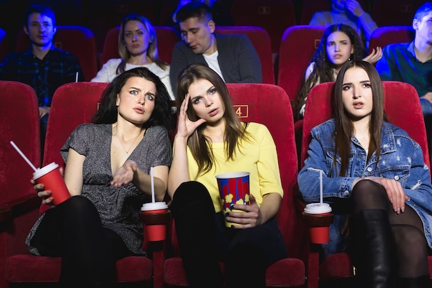 Девушки смотрят действительно скучный фильм в кинотеатре.
