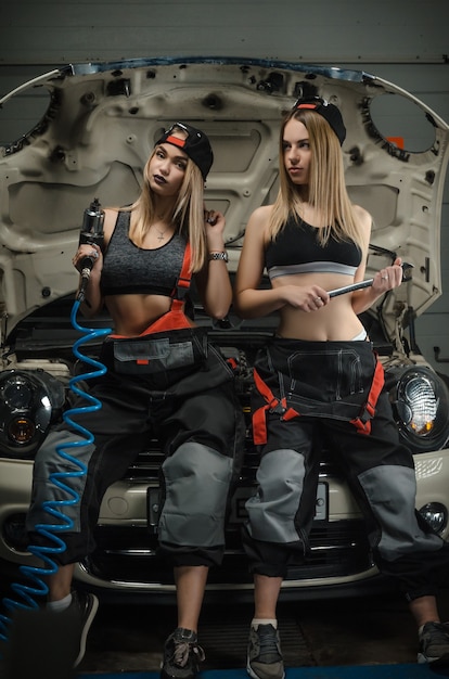 Photo girls in the way mechanics repair cars