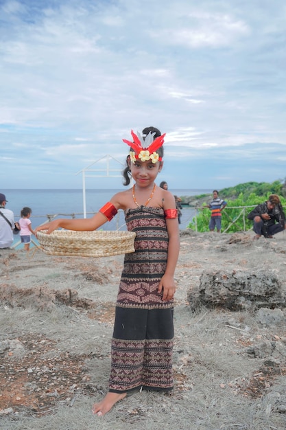 girls wear clothes and cultural attributes of sabu island, holding the rice sieve