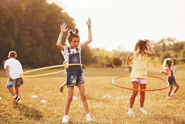 Girls with circle fitness tool. Group of kids have active weekend in the field.