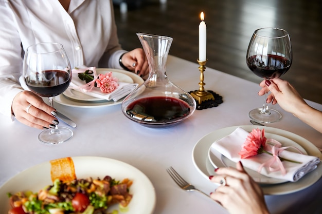 Girls with glasses of red wine are sitting at a served table in a restaurant