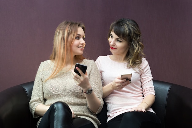 Ragazze con telefoni cellulari nelle loro mani.