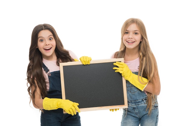 Girls with rubber protective gloves ready for cleaning. Household duties. Little helper. Girls cute kids cleaning according to duty, blackboard copy space. Cleaning check list. Kids cleaning together.