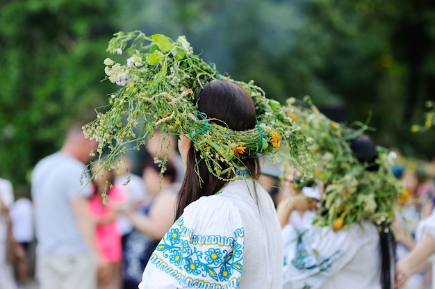 野生の花の花輪を持つ女の子はラウンドダンスを運転